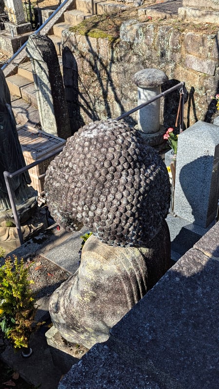The back view of a Buddha statue with an afro hairstyle.